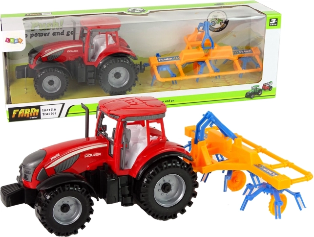 Rdeč traktor z grabljalnikom s frikcijskim pogonom